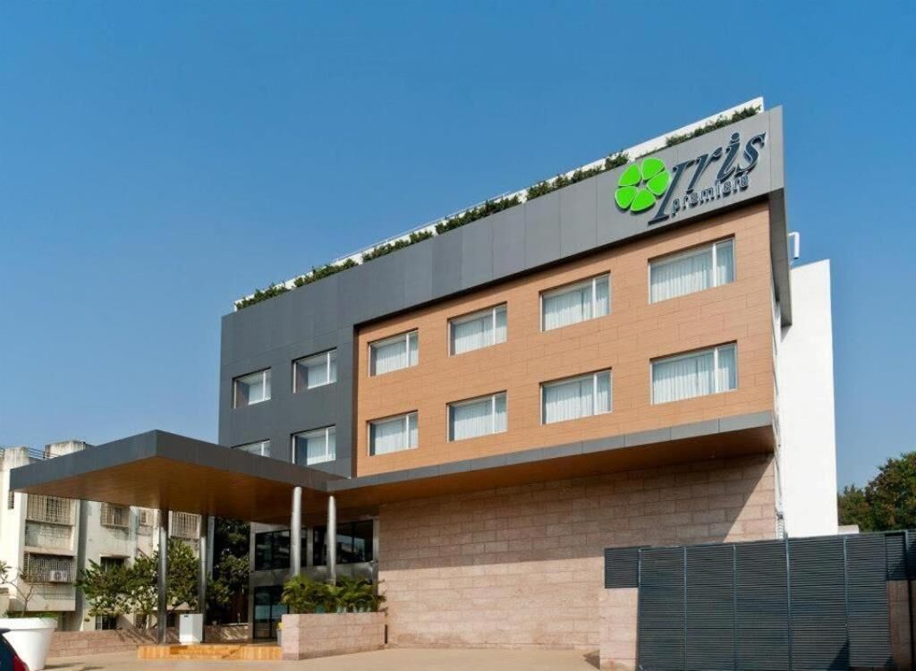 Un edificio moderno con un logotipo destacado en la fachada, varias ventanas y un área de entrada cubierta.
