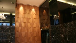 A modern interior with a wooden wall panel design, a marble floor, and a chandelier. - Iris Premire (Ahmednagar)