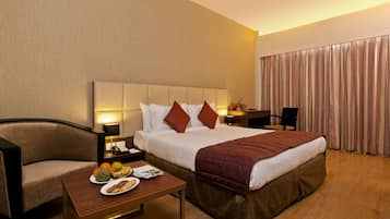 A hotel room with a bed, a desk, a chair, and a table with food.