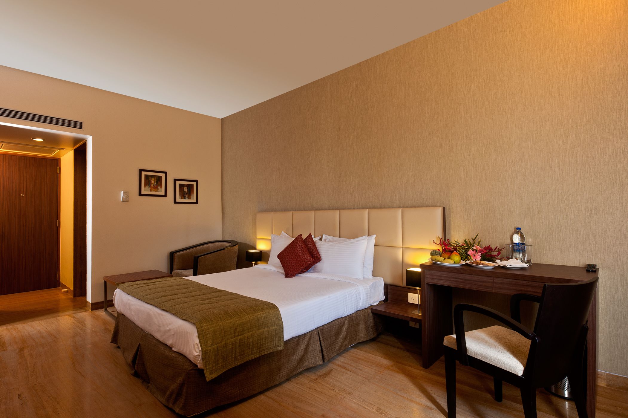 Una habitación de hotel con cama, mesita de noche, silla y escritorio con lámpara.