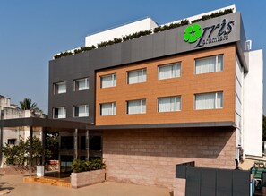 A modern hotel with a flat roof, a green logo, and a brick facade. - Iris Premire (Ahmednagar)