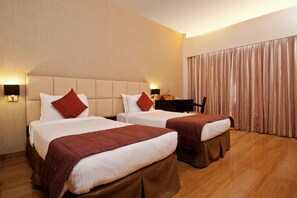 A hotel room with two beds, a desk, and a curtain. - Iris Premire (Ahmednagar)