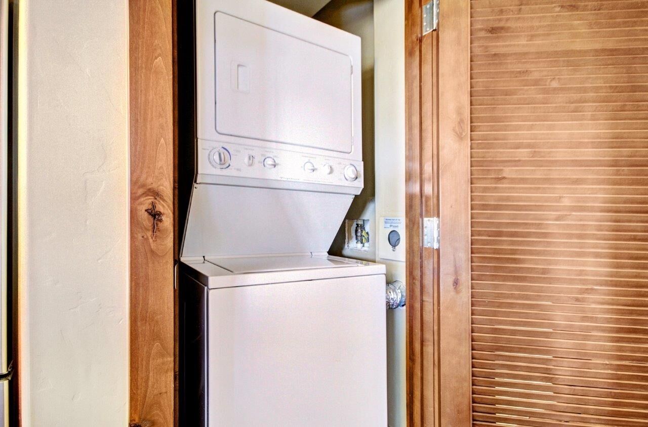 A compact washer and dryer unit in a narrow space, likely in a residential or small commercial setting.