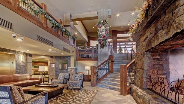 A spacious lobby with a fireplace, a staircase, and a seating area with a patterned rug. - At Base Of Peak 8, Steps From Winter Activities 3 Bedroom Condo by RedAwning (Breckenridge)