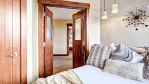 A bedroom with a bed, patterned pillows, a decorative wall piece, and a wooden door. - At Base Of Peak 8, Steps From Winter Activities 3 Bedroom Condo by RedAwning (Breckenridge)