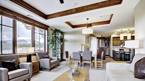 A spacious living room with a sofa, armchairs, a coffee table, and a dining area with chairs and a table. There is a large window with a view of a mountain. - At Base Of Peak 8, Steps From Winter Activities 3 Bedroom Condo by RedAwning (Breckenridge)
