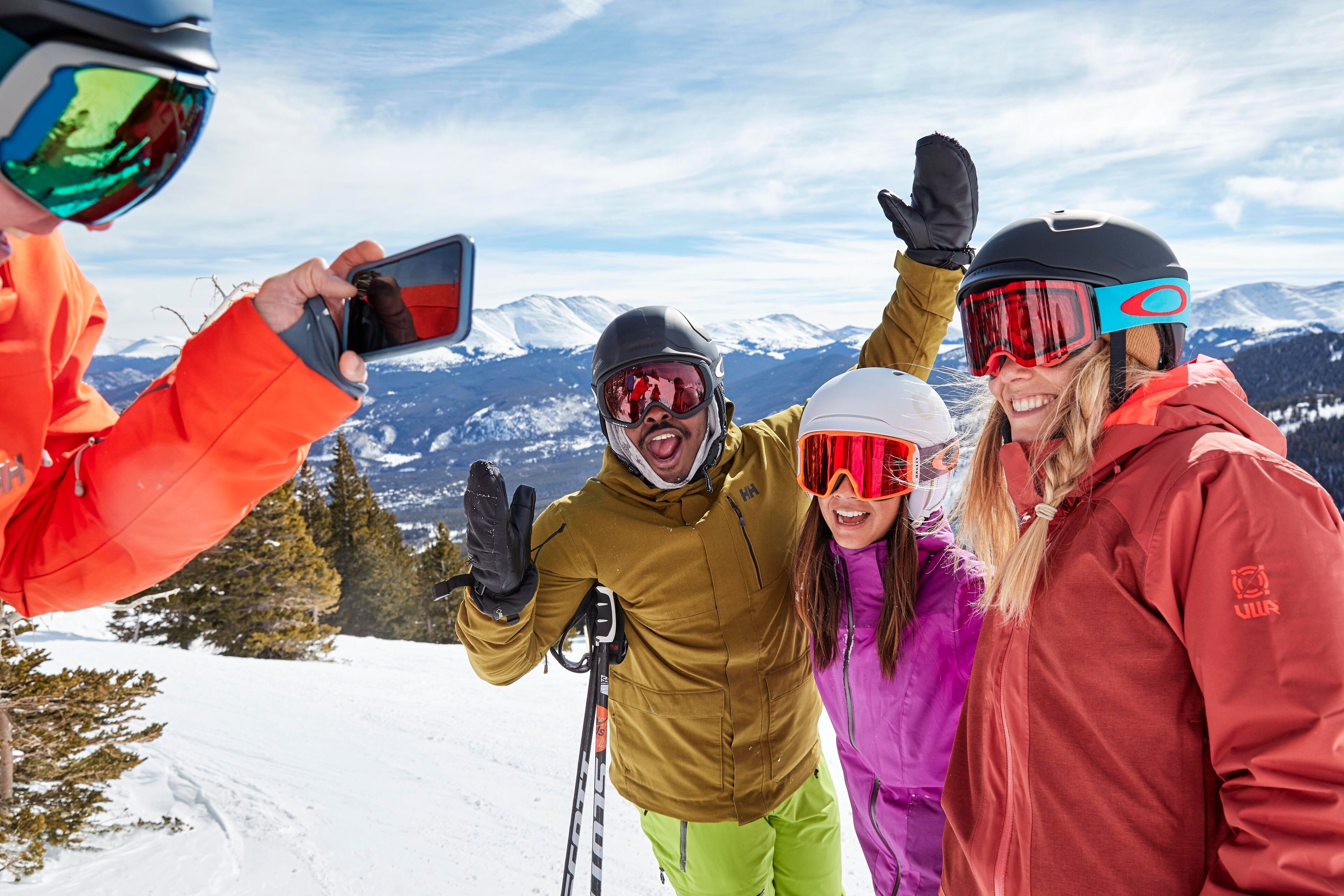 A group of people on a snowy mountain with ski equipment, taking a selfie.