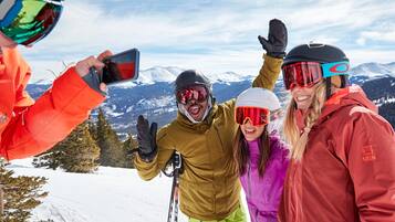 Een groep mensen op een besneeuwde berg met ski-uitrusting, die een selfie maken.