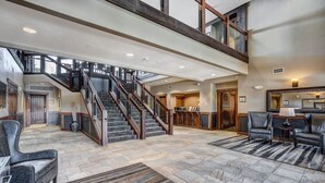 A spacious lobby with a staircase, leather seating, and a stone floor. - Premier 2br  At The Base Of Peak 7 2 Bedroom Condo by RedAwning (Breckenridge)