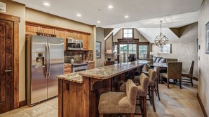 A spacious kitchen with a large island, wooden cabinets, and a stainless steel refrigerator. - Premier 2br  At The Base Of Peak 7 2 Bedroom Condo by RedAwning (Breckenridge)