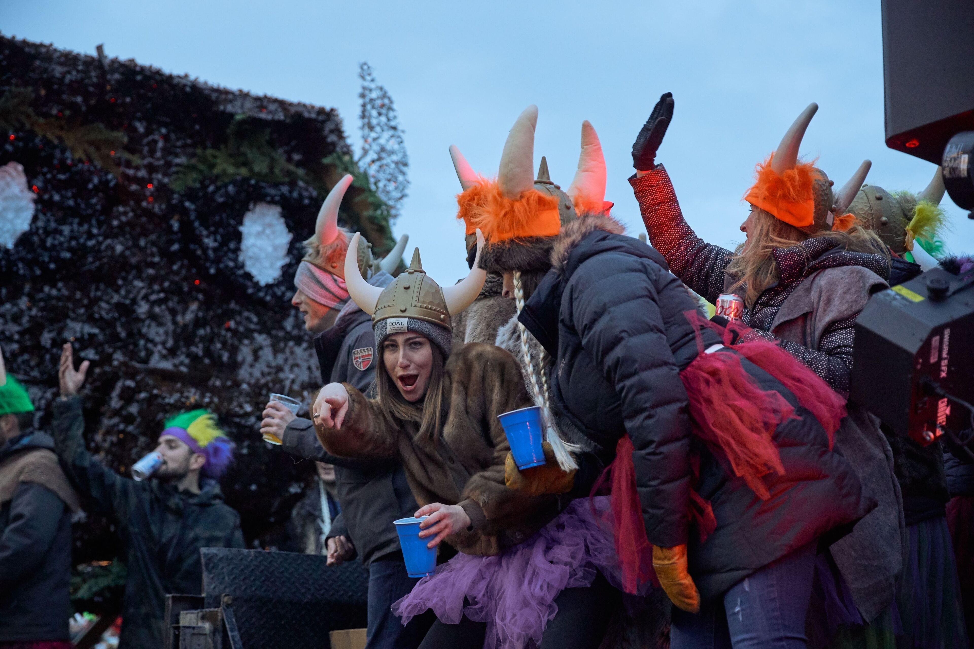 Eine Gruppe von Menschen in Winterkleidung, manche mit Tierkopfschmuck, versammelt sich draußen.