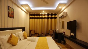 A hotel room with a large bed, a desk, a television, and a ceiling fan. - Paradise Ganga - A River Side Hotel (Rishikesh)