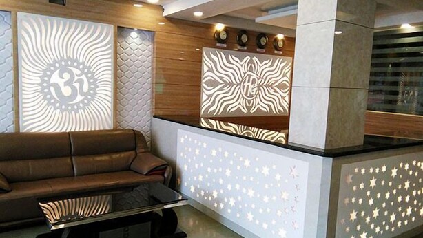A modern reception area with a leather sofa, a glass coffee table, and decorative wall panels with geometric patterns. - Paradise Ganga - A River Side Hotel (Rishikesh)