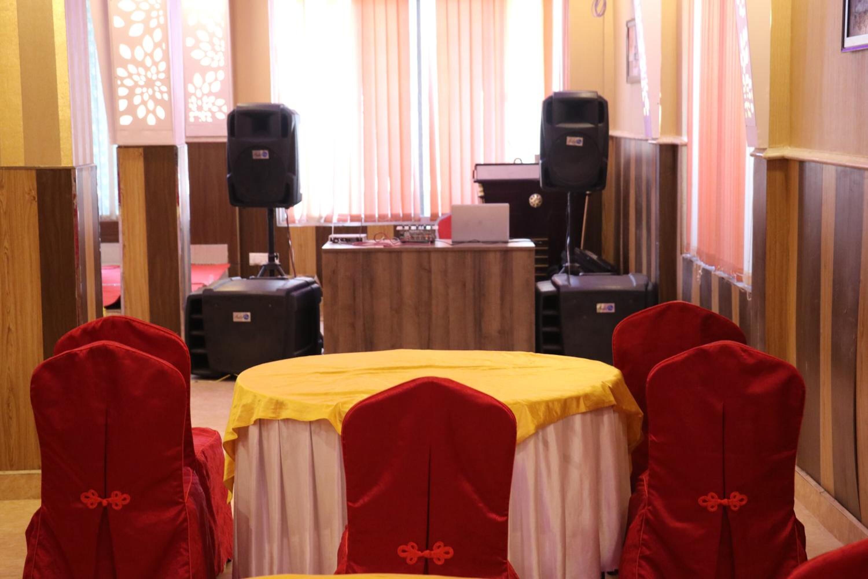 A conference room with a yellow table, red chairs with key designs, and two speakers.
