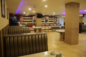 A restaurant interior with booths, a counter, and a variety of food items on display. - Paradise Ganga - A River Side Hotel (Rishikesh)