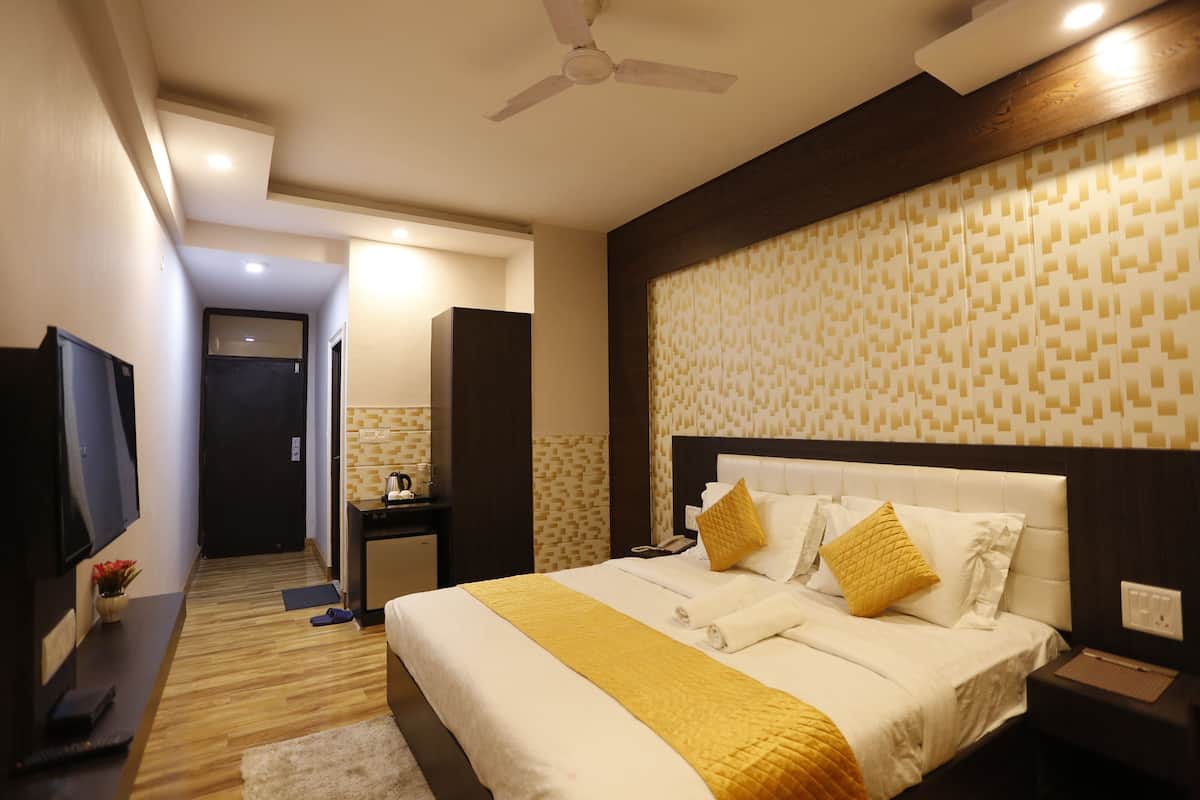A hotel room with a bed, bedside table, TV, and a ceiling fan.