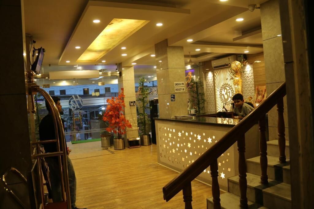A hotel reception area with a reception desk, a staircase, and a view of the lobby.