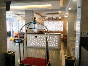 A modern lobby with a glass partition, a reception desk with a star-patterned backlit panel, and a ceiling with recessed lighting. - Paradise Ganga - A River Side Hotel (Rishikesh)