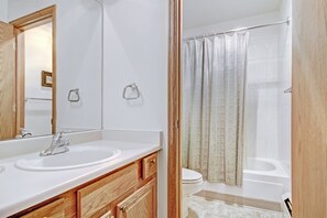 Un baño con lavamanos doble, un espejo, inodoro y ducha con cortina.