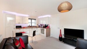 A modern living room with a sofa, TV, and dining area. - The Coach House (Derby)