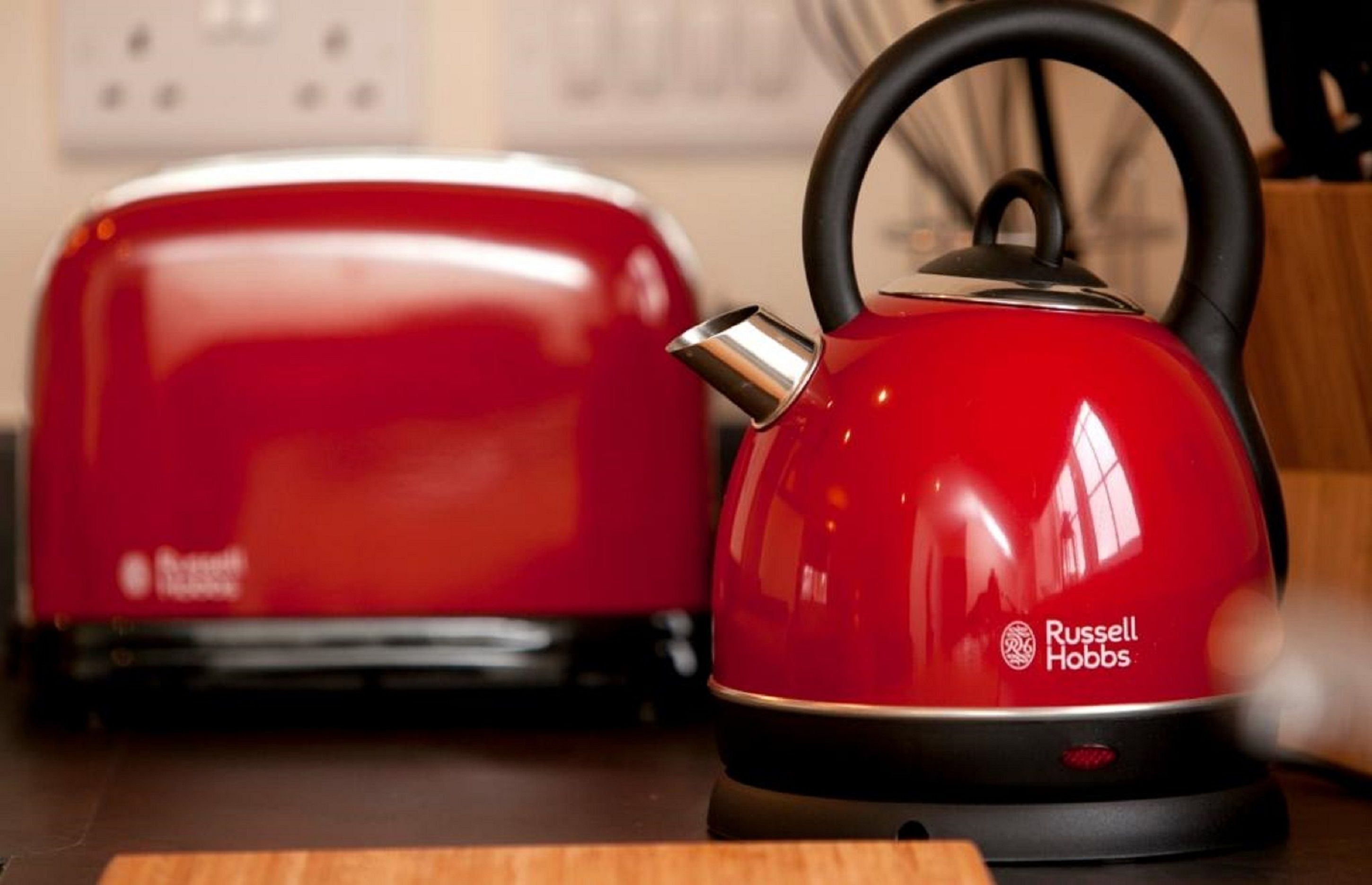 A red kettle and toaster on a kitchen counter.