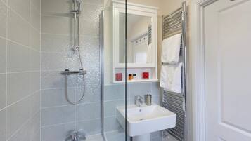 Baño con ducha, lavamanos y espejo.
