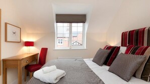 A bedroom with a bed, a desk, a chair, a window, and a framed picture on the wall. - The Twain (Derby)