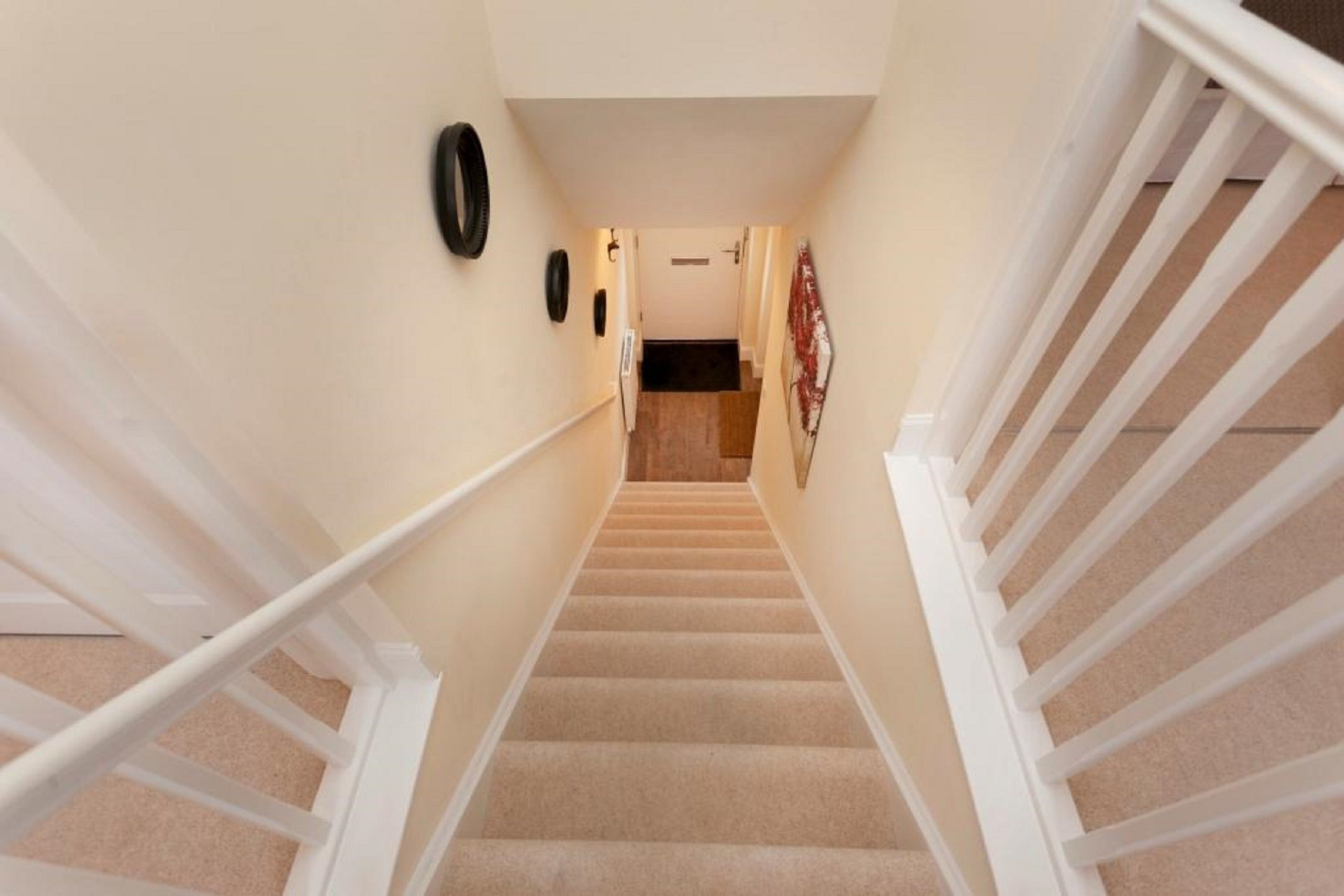 A carpeted staircase with white railings, a door at the top, and a wall-mounted clock.