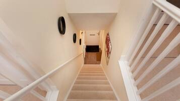 A carpeted staircase with white railings, a door at the top, and a wall-mounted clock.