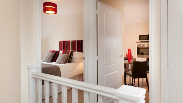 A bedroom with a bed, a red and white striped headboard, and a red pendant light. - The Twain (Derby)
