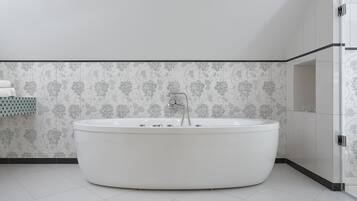 Un bany modern amb una banyera independent, parets revestides i una cabina de dutxa de vidre.