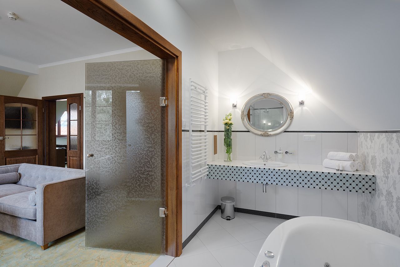 A modern bathroom with a freestanding bathtub, a round mirror, and a patterned sink vanity.