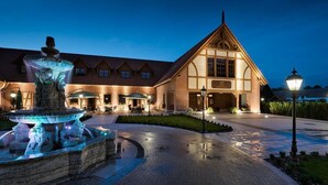 Un hotel con una gran fuente, mobiliario exterior e iluminación destacada en la entrada.