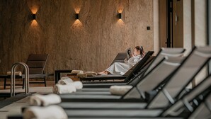 Zona de spa con sillones reclinables, toallas e iluminación en la pared.