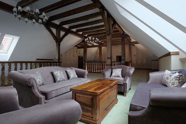 A loft-style living room with high ceilings, exposed wooden beams, and a large window providing natural light. - Hotel Poledno (Bukowiec)