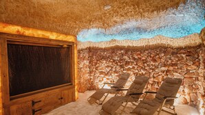 Una habitación con pared de piedra, un armario de madera y tres sillones reclinables.