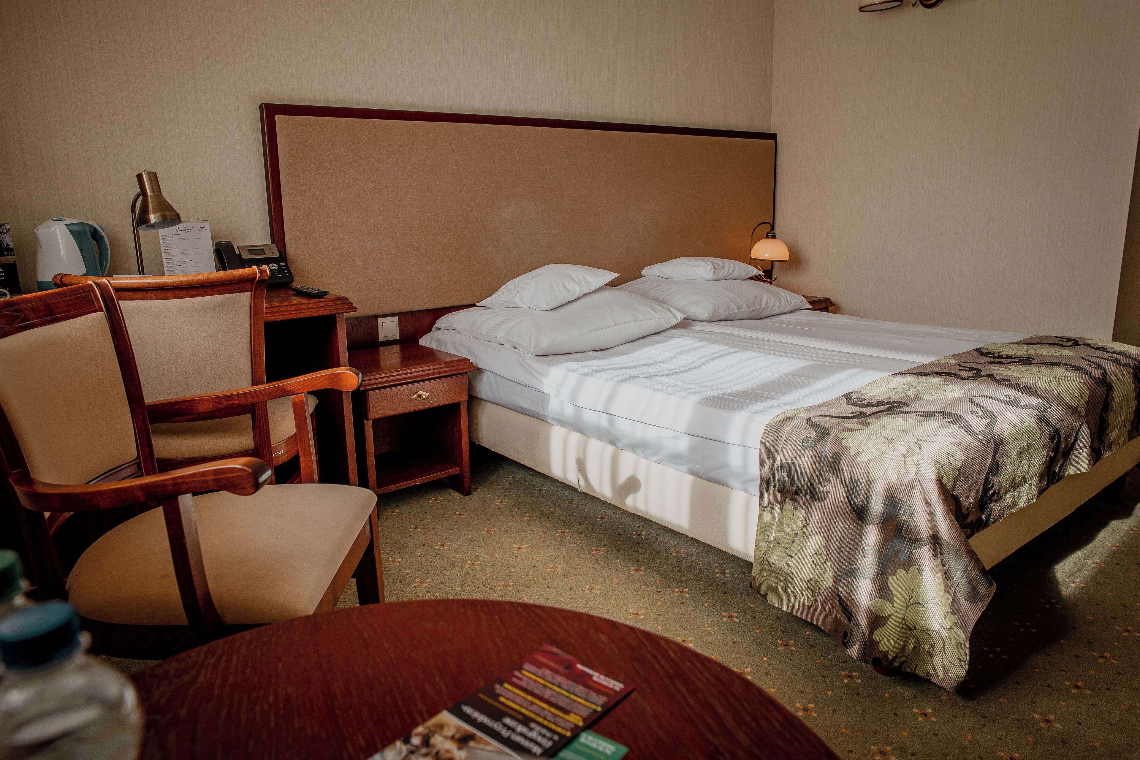 Une chambre d’hôtel comprenant un lit, un bureau avec une chaise, une table de chevet et une lampe.