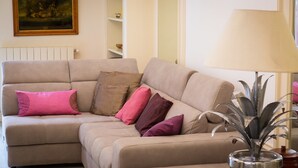A beige sectional sofa with multiple cushions in various colors, a floor lamp, and a painting on the wall. - Rental in Rome Augustus Terrace Deluxe (Rome)