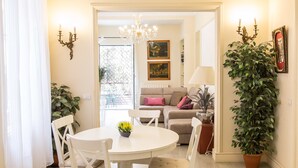 A dining area with a round table, chairs, and a potted plant. There is a sofa with cushions in the background. - Rental in Rome Augustus Terrace Deluxe (Rome)