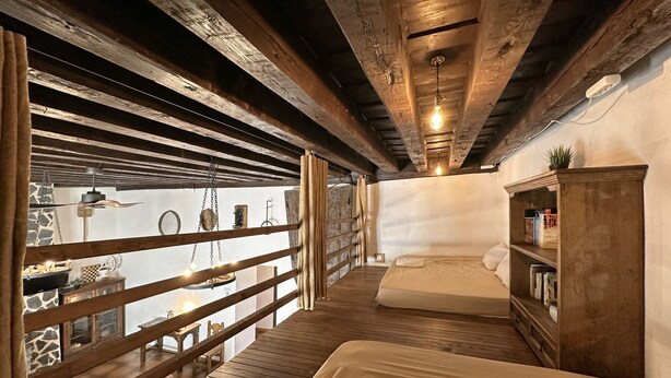 A bedroom with a wooden ceiling, a bed, a bookshelf, and a view through a wooden railing. - Palacio de Velamazán (Velamazan)
