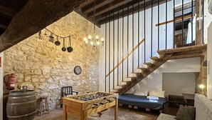 A cozy room with a foosball table, a stone wall, a wooden staircase, and a bed. - Palacio de Velamazán (Velamazan)