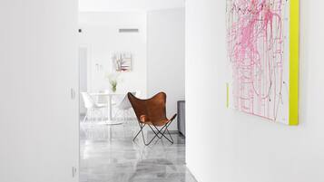 Un interior moderno con una zona de comedor, una silla marrón y un cuadro abstracto grande en la pared.
