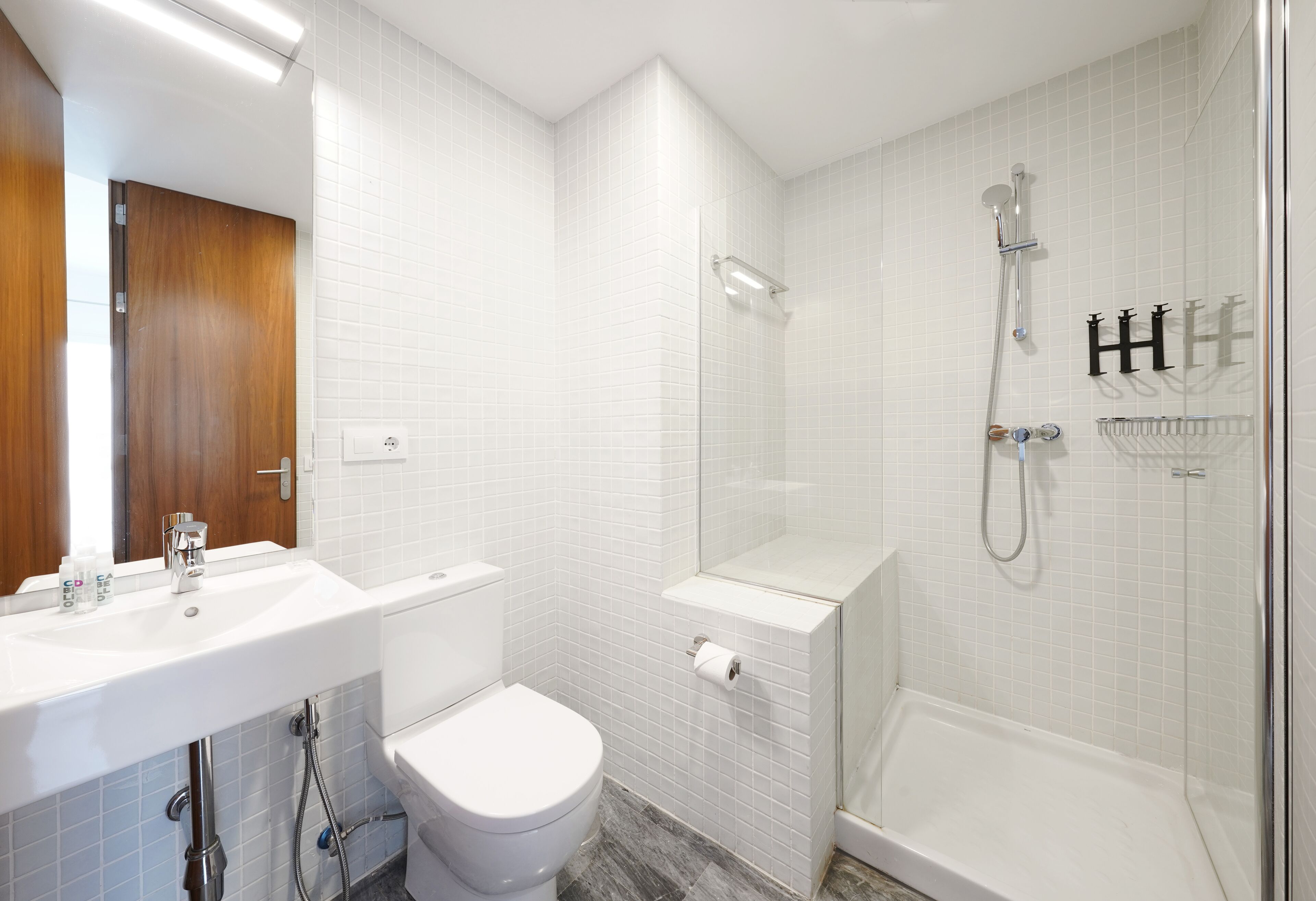 A modern bathroom with a white sink, toilet, and shower area.