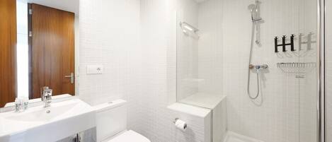 Et moderne badeværelse med en hvid vask, toilet og bruseområde.