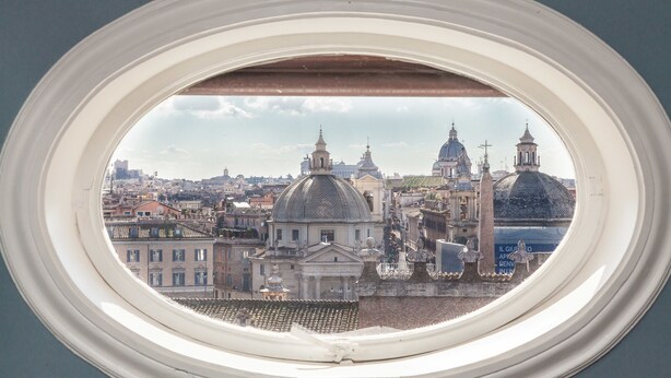 A view through a window of a cityscape with historical architecture, including domed buildings and a prominent church. - Rental in Rome Flaminio View Suite (Rome)