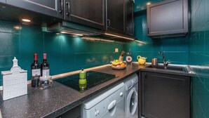 A kitchen with dark cabinets, a black countertop, a built-in stove, a washing machine, and a sink. - Rental in Rome Flaminio View Suite (Rome)
