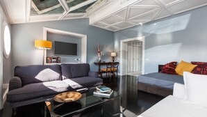 A modern living room with a sofa, a coffee table, a TV, and a dining area with chairs and a table. - Rental in Rome Flaminio View Suite (Rome)