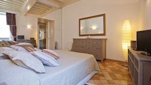 A bedroom with a bed, a dresser, a television, and a mirror. - Rental in Rome Crociferi 1 (Rome)
