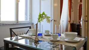 A dining table with a glass top, surrounded by white bowls and cups, and a vase with a plant. - Rental in Rome Crociferi 1 (Rome)
