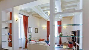 A spacious living area with a sofa, glass shelves, and a laptop. - Rental in Rome Crociferi 1 (Rome)